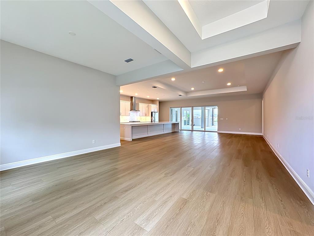 An open-concept living area features light wood-look flooring, a tray ceiling, and a kitchen island — 12422 STONEGATE TRAIL, PARRISH, FL