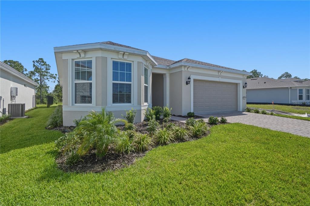 A single-story house with a beige stucco exterior, a two-car garage, and a landscaped yard — 6401 WHITE WILLOW COURT, ST CLOUD, FL