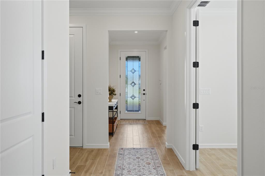 A bright entryway features light wood-look tile flooring, white walls, and a glass-paneled front door — 6401 WHITE WILLOW COURT, ST CLOUD, FL