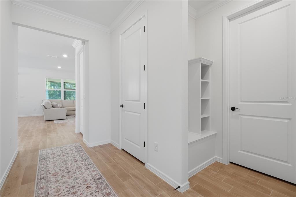 A bright hallway features white doors, light wood-look flooring, and a built-in storage bench — 6401 WHITE WILLOW COURT, ST CLOUD, FL