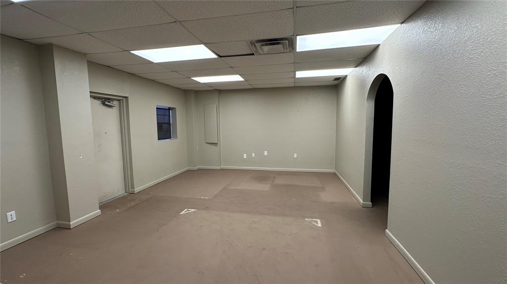 An empty office room features beige walls, a drop ceiling, and bare concrete flooring — 3120-3126 REYNOLDS ROAD, LAKELAND, FL