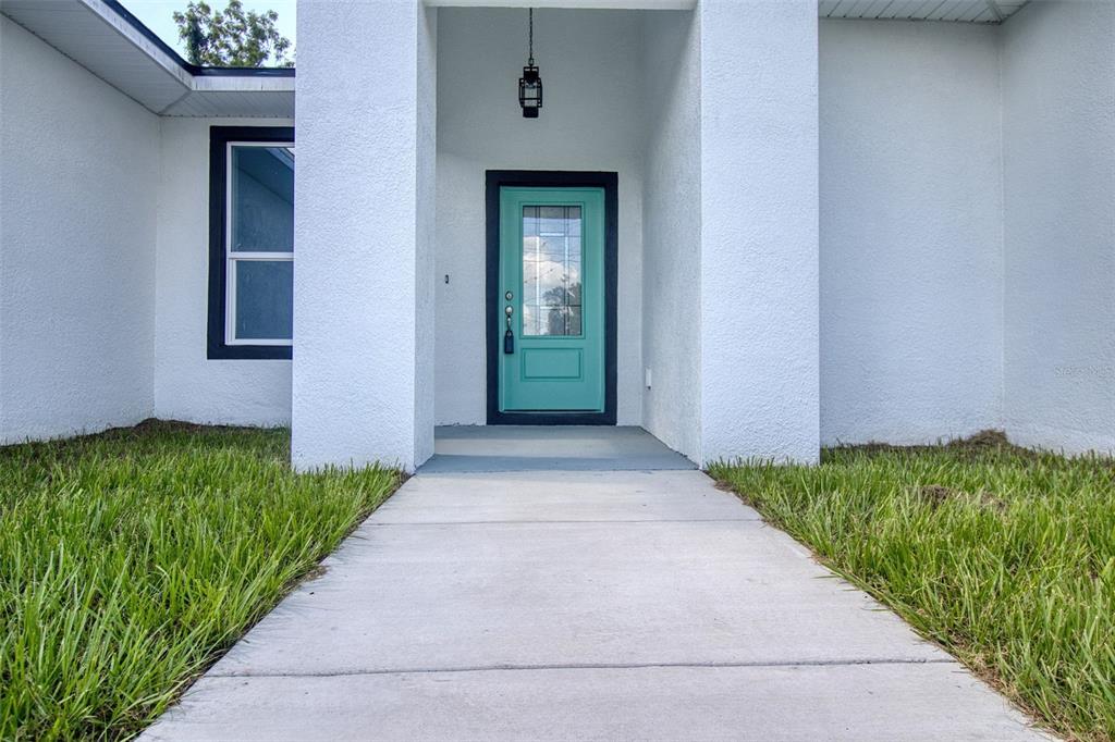 An open-concept kitchen and living area features gray cabinetry, granite countertops, and tile flooring — 1246 HERSCHELL STREET, LAKELAND, FL