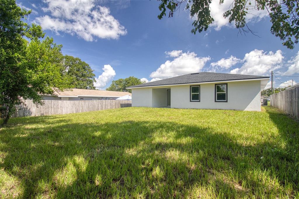 An open-concept living and kitchen area features tile flooring, a chandelier, and sliding glass doors — 1246 HERSCHELL STREET, LAKELAND, FL