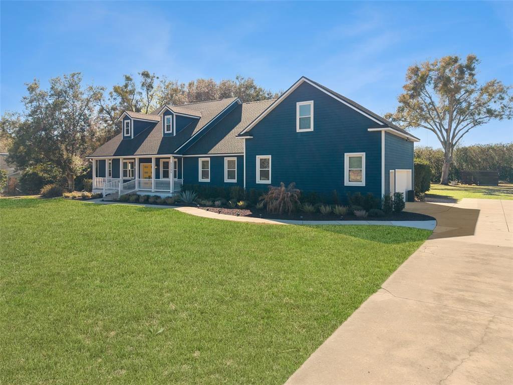 A two-story blue house with a front porch and a large grassy lawn — 32345 WOLFS TRAIL, SORRENTO, FL