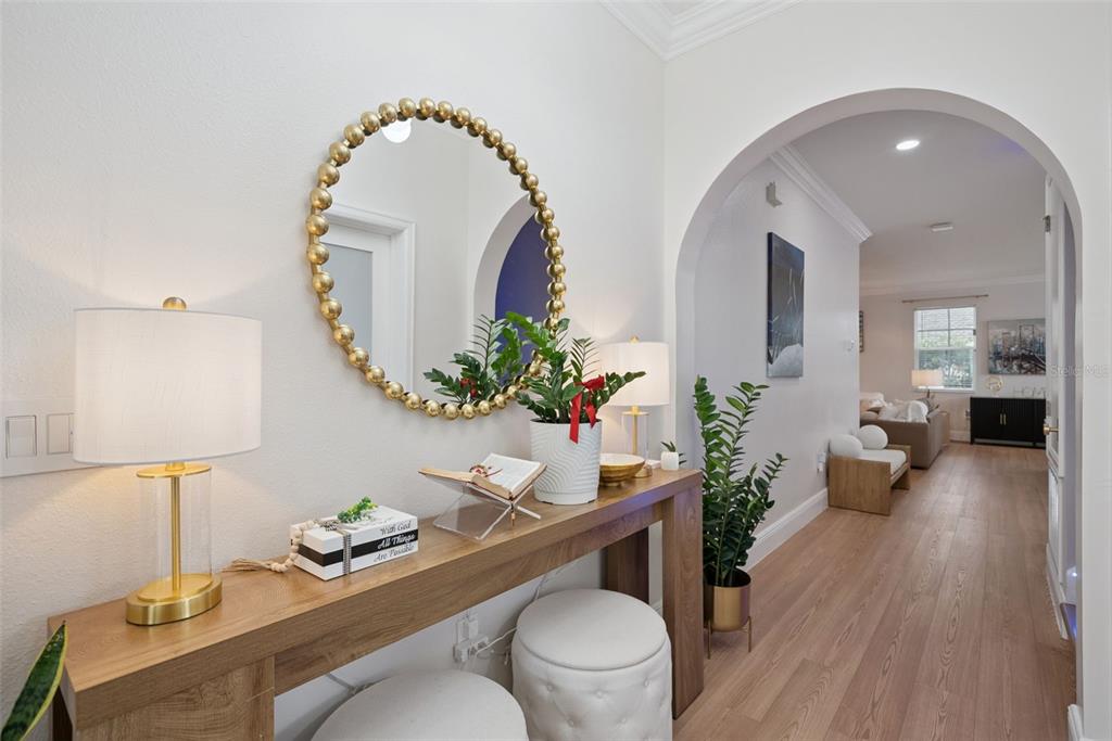 A wooden console table with a gold-rimmed mirror sits in a bright, arched entryway — 11479 SATIRE STREET, ORLANDO, FL