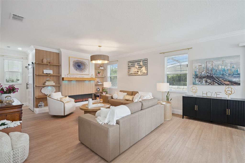 A living room features light wood flooring, a fireplace with wood paneling, and neutral furniture — 11479 SATIRE STREET, ORLANDO, FL