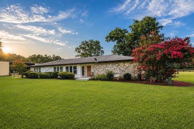 An aerial view shows a rectangular sand riding arena surrounded by grass and dense trees — 16525 SW 5TH PLACE, NEWBERRY, FL