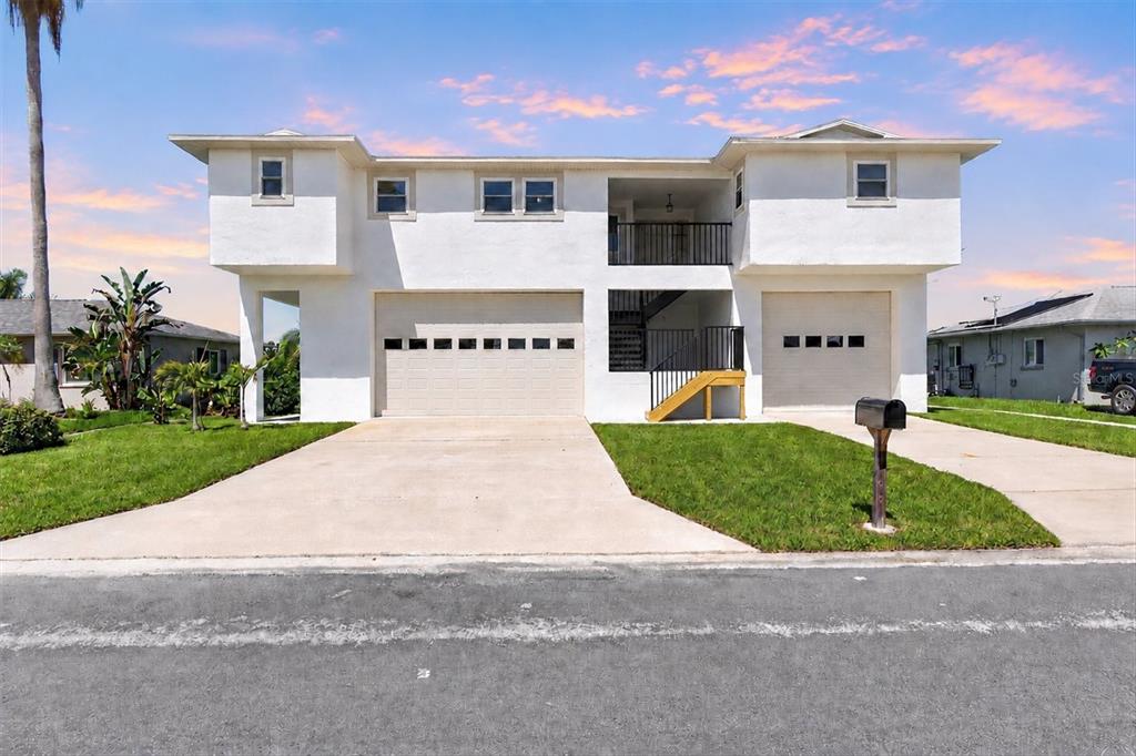 A two-story white house features two garages, a central staircase, and a balcony — 4159 CAMELIA DRIVE, HERNANDO BEACH, FL