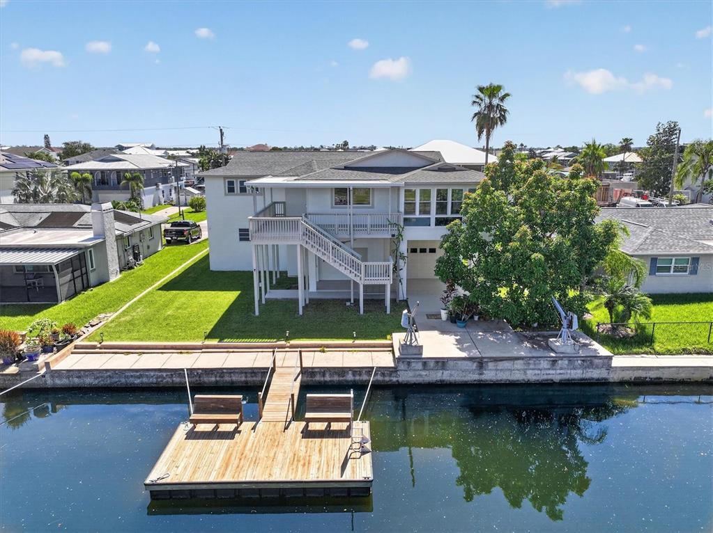 An elevated house with a wooden deck and boat dock sits along a canal — 4159 CAMELIA DRIVE, HERNANDO BEACH, FL