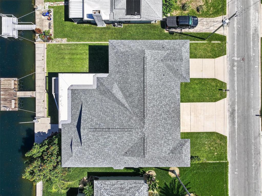 An aerial view shows a house with a gray shingled roof, driveway, and waterfront dock — 4159 CAMELIA DRIVE, HERNANDO BEACH, FL