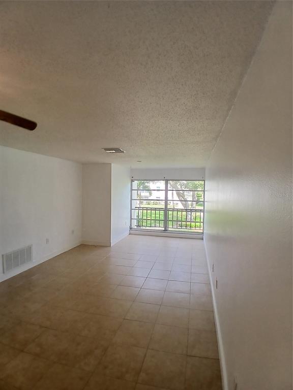 An empty room with beige tile flooring, white walls, and a large window with a balcony — 2700 BAYSHORE BOULEVARD UNIT 2211, DUNEDIN, FL
