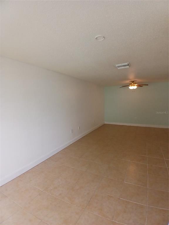 An empty room features white walls, a light green accent wall, and beige tile flooring — 2700 BAYSHORE BOULEVARD UNIT 2211, DUNEDIN, FL