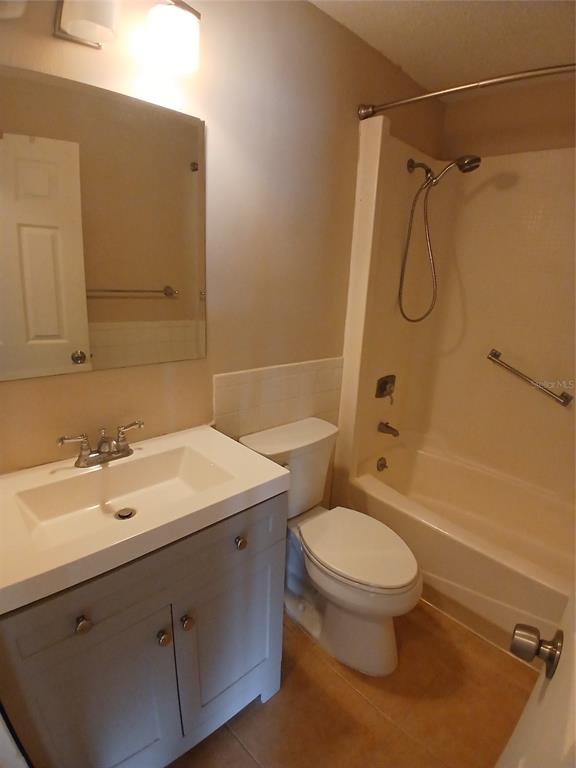 A bathroom features a gray vanity, a white toilet, and a shower-tub combination — 2700 BAYSHORE BOULEVARD UNIT 2211, DUNEDIN, FL