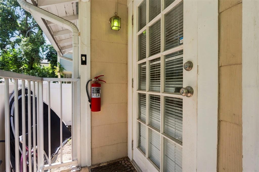 A red fire extinguisher is mounted on the exterior wall next to a glass-paned door — 406 10TH AVENUE NE, ST PETERSBURG, FL