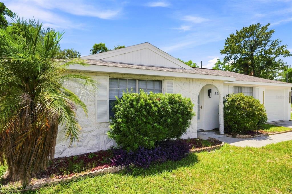 A white single-story house with a stone facade, a palm tree, and a front lawn — 6214 WESTPORT DRIVE, PORT RICHEY, FL