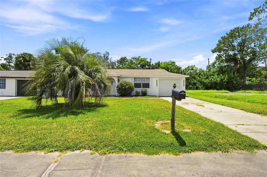 A single-story house with a white exterior, a front lawn, and a concrete driveway — 6214 WESTPORT DRIVE, PORT RICHEY, FL