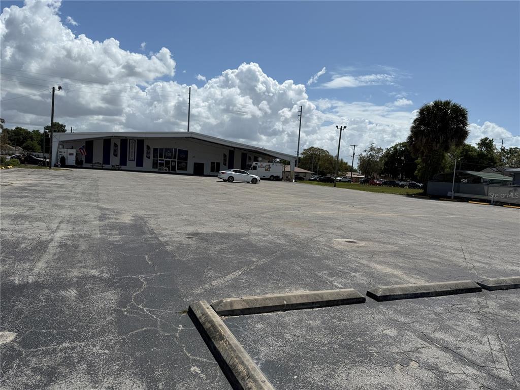 A large, paved parking lot sits in front of a commercial building under a cloudy sky — 2001 S BAY STREET, EUSTIS, FL