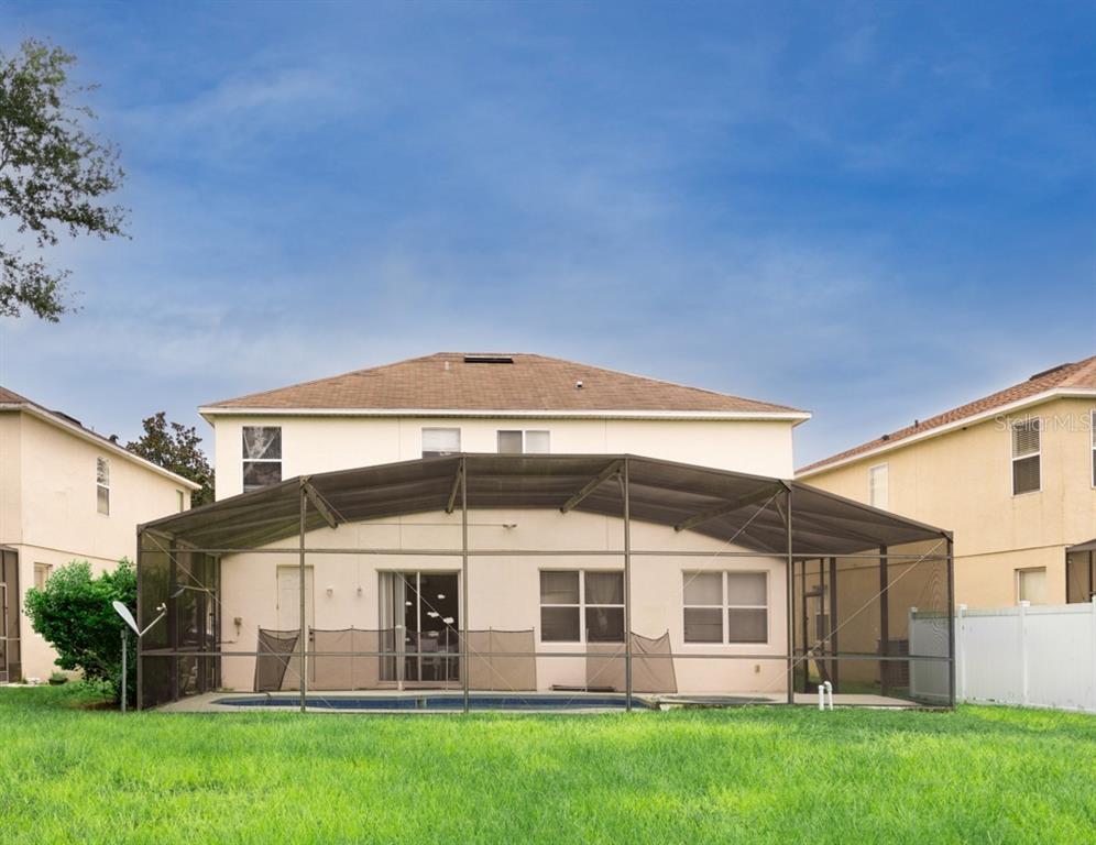 The rear exterior of a two-story house features a screened-in pool and a grassy yard — 625 KETTERING ROAD, DAVENPORT, FL