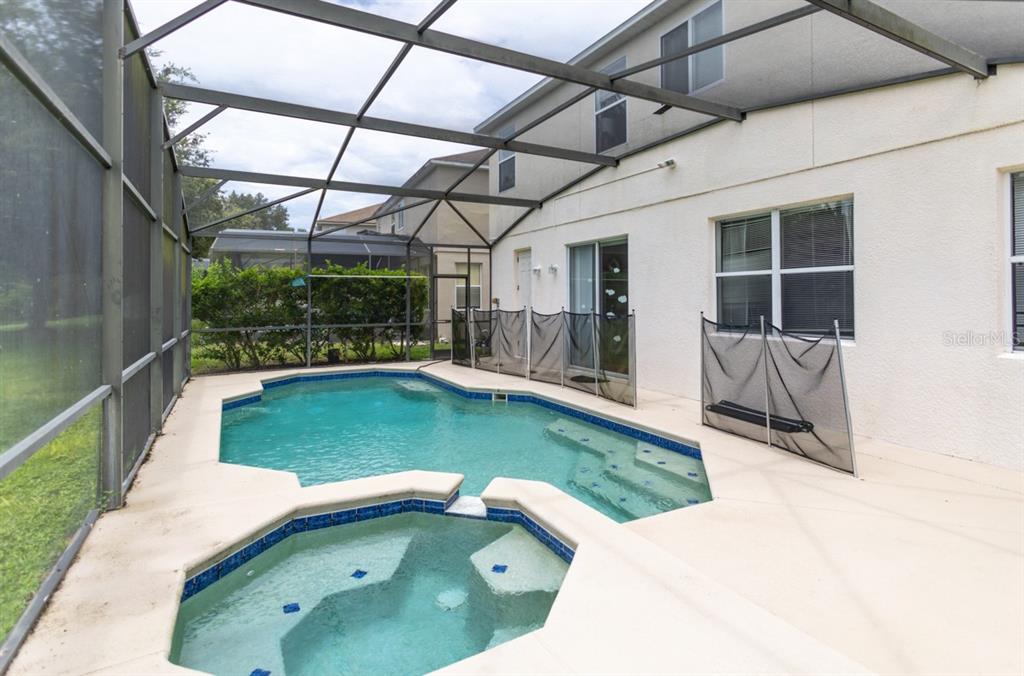 A screened-in patio features a swimming pool, a built-in spa, and a safety fence — 625 KETTERING ROAD, DAVENPORT, FL