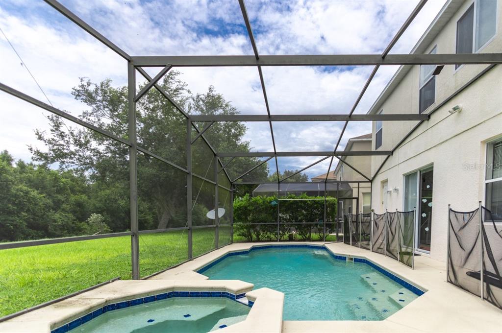 A screened-in patio features a swimming pool and a hot tub next to a house — 625 KETTERING ROAD, DAVENPORT, FL