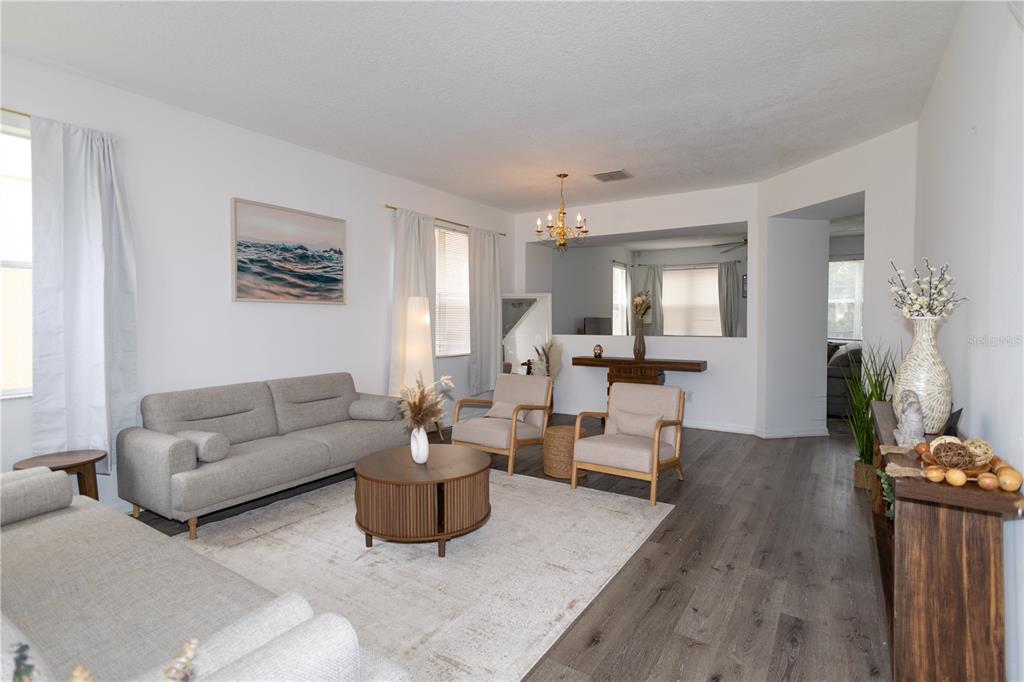 A living room features gray wood-look flooring, a light-colored area rug, and neutral-toned furniture — 625 KETTERING ROAD, DAVENPORT, FL