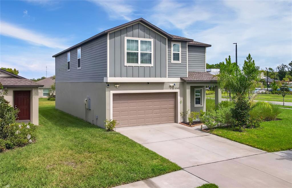 A two-story house with gray siding, a tan stucco lower level, and a two-car garage — 22547 STORYBOOK CABIN WAY, LAND O LAKES, FL