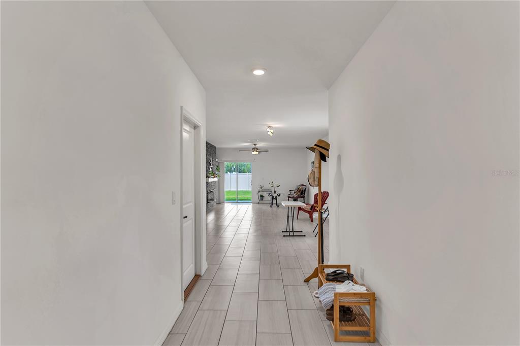 A hallway with light tile flooring leads to an open living area with a fireplace — 22547 STORYBOOK CABIN WAY, LAND O LAKES, FL