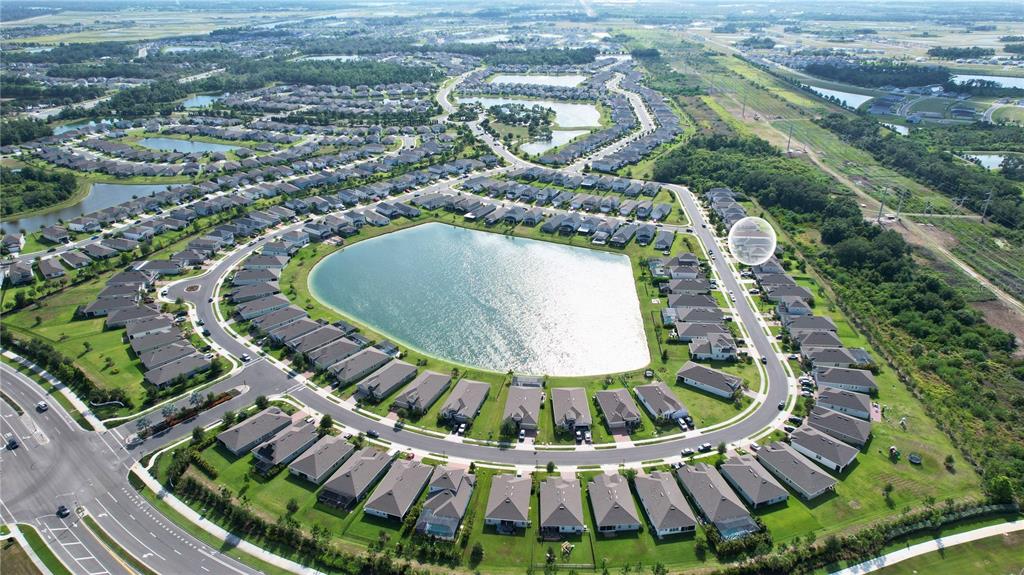 An aerial view shows a suburban neighborhood with houses surrounding a large central lake — 11636 LITTLE RIVER WAY, PARRISH, FL