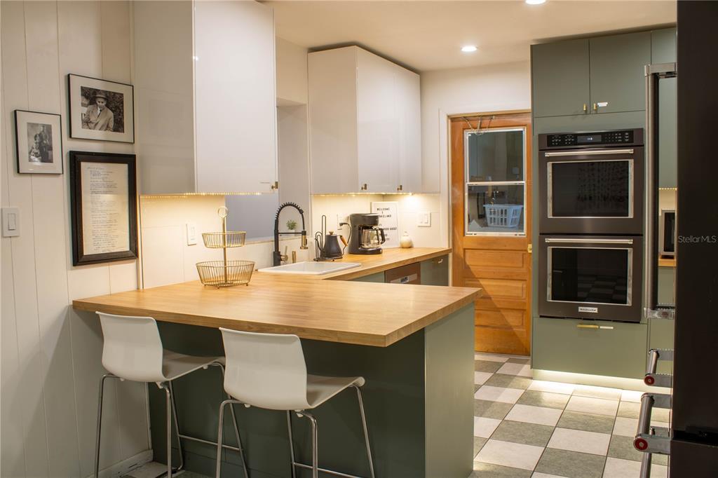 A kitchen features green and white cabinets, a wood countertop, and a double wall oven — 5139 IDLEWOOD LANE, LAKELAND, FL