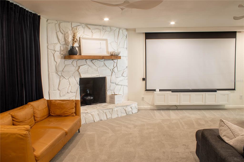 A living room features a white stone fireplace, a projector screen, and a leather sofa — 5139 IDLEWOOD LANE, LAKELAND, FL