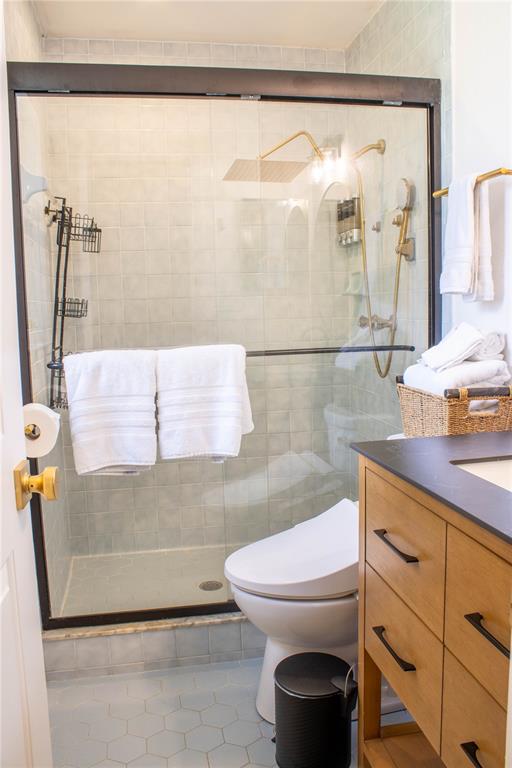 A bathroom features a glass-enclosed shower, a toilet, and a wooden vanity with black hardware — 5139 IDLEWOOD LANE, LAKELAND, FL