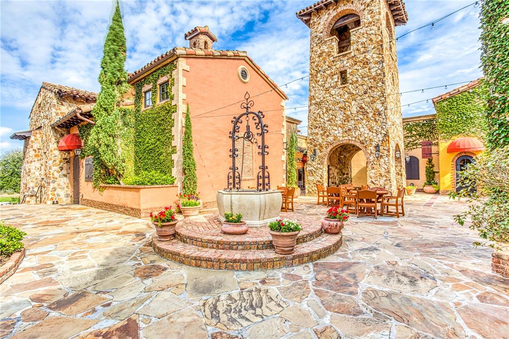 A stone courtyard features a central wishing well, outdoor seating, and Mediterranean-style buildings — 16241 RAVENNA COURT, MONTVERDE, FL