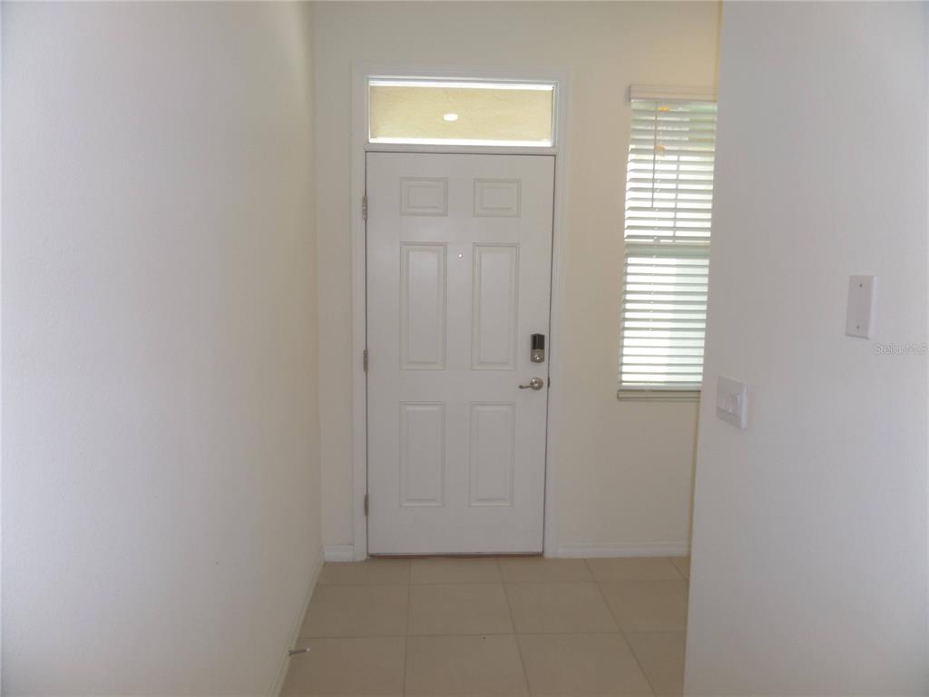 A white front door with a transom window opens into a tiled entryway — 5039 STOKES WAY, WILDWOOD, FL