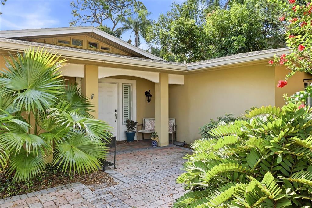 A paved walkway leads to the front entrance of a house with tan exterior walls — 1041 CITRUS AVENUE, SARASOTA, FL