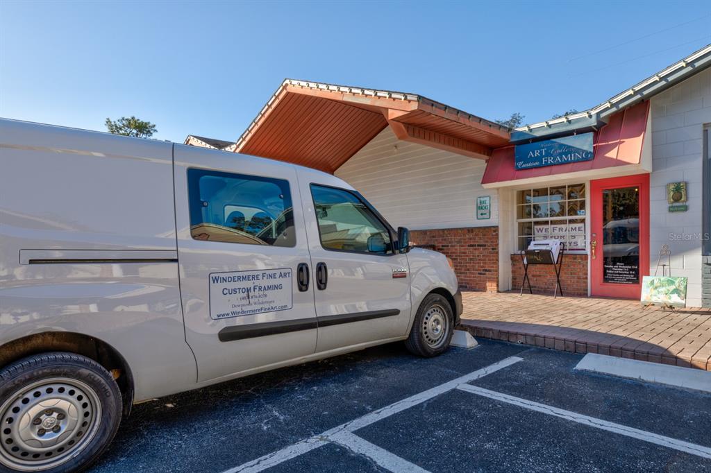 A white work van is parked in front of a brick-accented commercial building entrance — 0 USA, WINDERMERE, FL