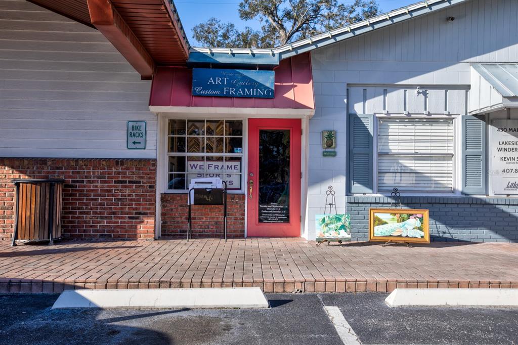 The exterior of a small storefront features a red door, brick base, and framed artwork — 0 USA, WINDERMERE, FL