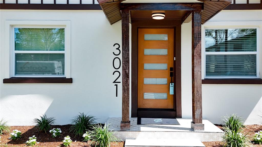 The exterior of a house features a wooden front door, house numbers, and two windows — 3021 GRANVILLE COURT N, ST PETERSBURG, FL