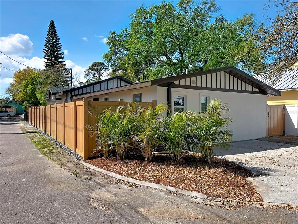 A tan fence runs alongside a light-colored house with a dark roof and palm trees — 3021 GRANVILLE COURT N, ST PETERSBURG, FL