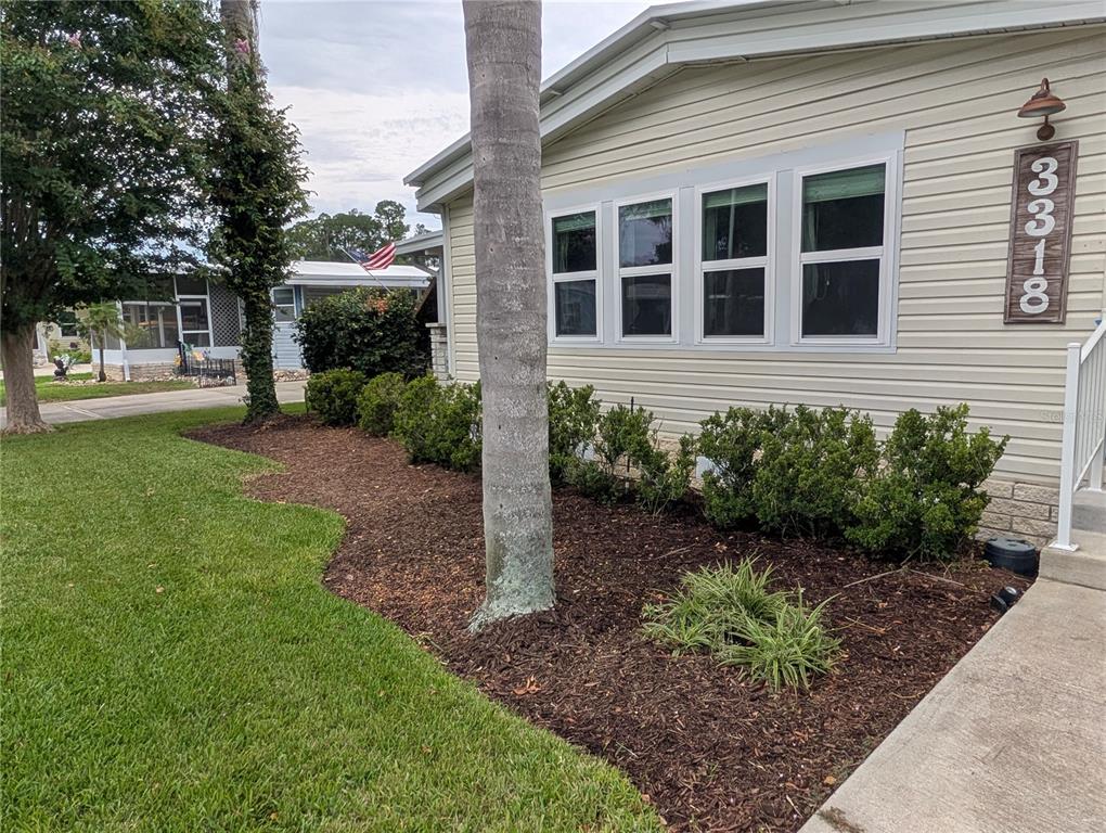 The exterior of a light-colored home features a palm tree, landscaping, and a house number — 3318 WEKIVA ROAD, TAVARES, FL