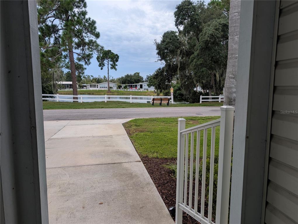 A view from a porch looking out at a concrete driveway, lawn, and small pond — 3318 WEKIVA ROAD, TAVARES, FL