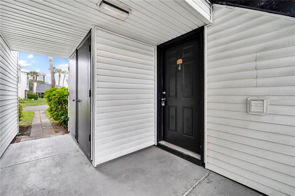 A grassy courtyard sits between two multi-story residential buildings under a bright blue sky — 654 HAVEN PLACE UNIT 654, TARPON SPRINGS, FL