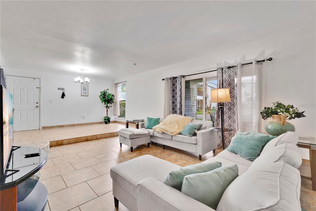 A living room features a sectional sofa, a glass-topped coffee table, and a television — 654 HAVEN PLACE UNIT 654, TARPON SPRINGS, FL