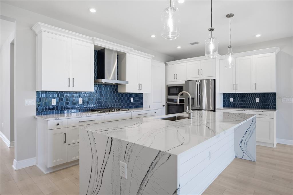 An open-concept kitchen and living area features a coffered ceiling, white cabinetry, and large windows — 1729 POINT GRACE ROAD, TAVARES, FL