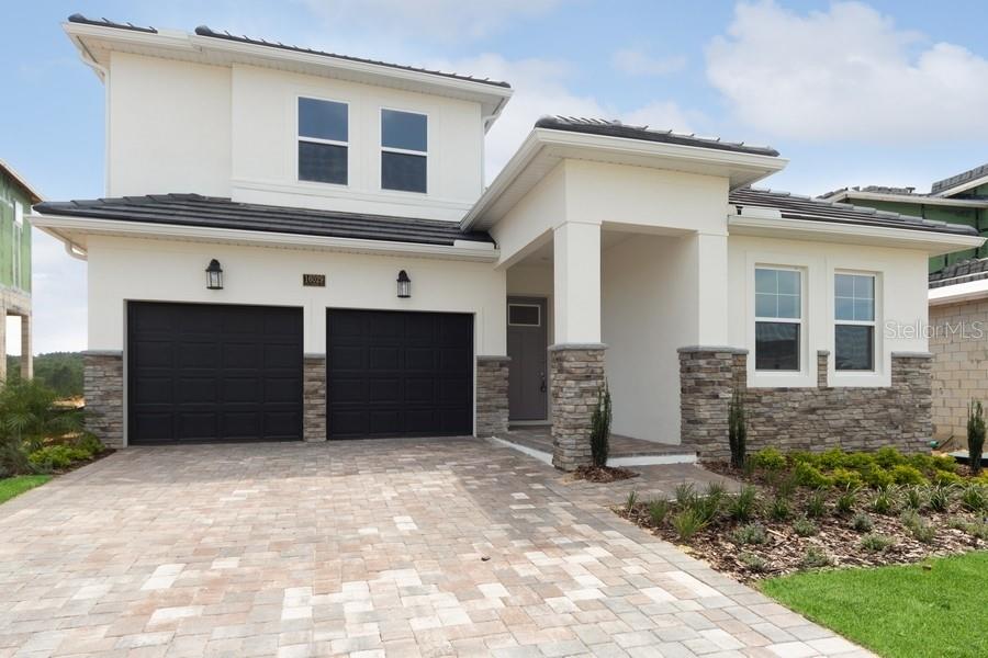 A two-story house with a white stucco exterior, stone accents, and a two-car garage — 16029 VOLTERRA POINT, MONTVERDE, FL