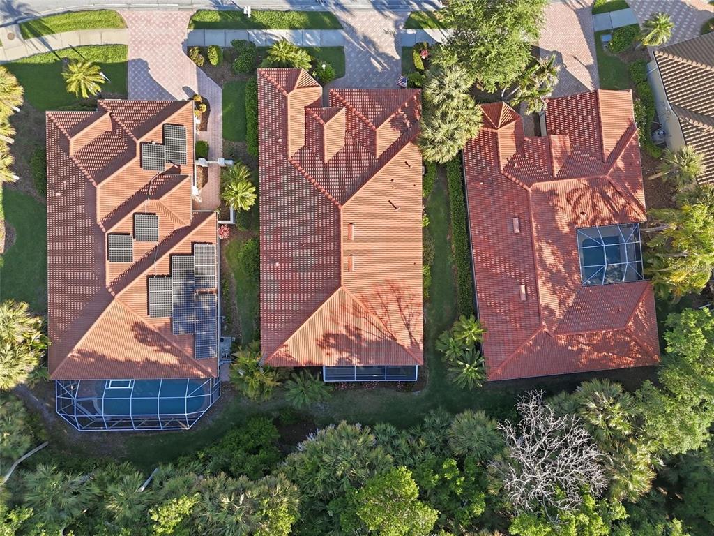 An aerial view shows three houses with red tile roofs and screened-in pool enclosures — 5127 HANGING MOSS LANE, SARASOTA, FL