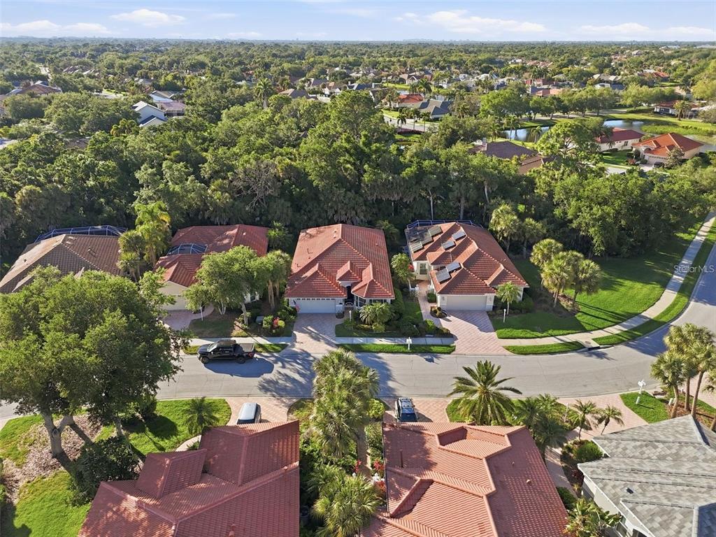 An aerial view shows several suburban houses with red tile roofs and surrounding green trees — 5127 HANGING MOSS LANE, SARASOTA, FL