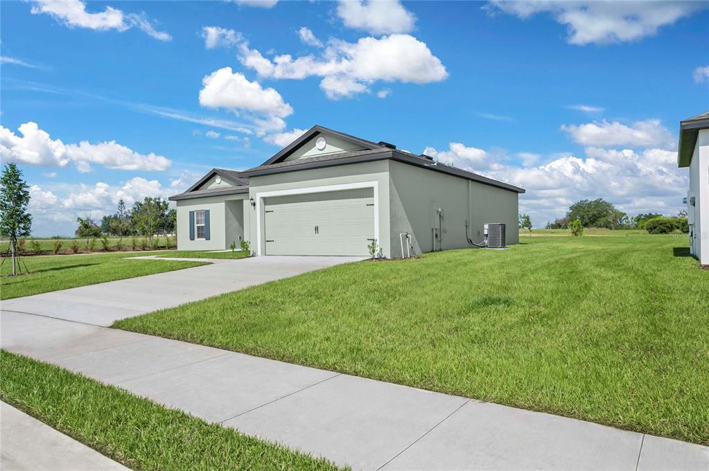 A light green single-story house with a two-car garage and a concrete driveway — 628 TANGELO TERRACE, BABSON PARK, FL