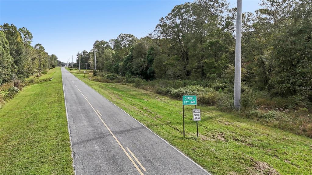 A paved road stretches into the distance past a Starke city limit sign and trees — W EDWARDS ROAD, STARKE, FL