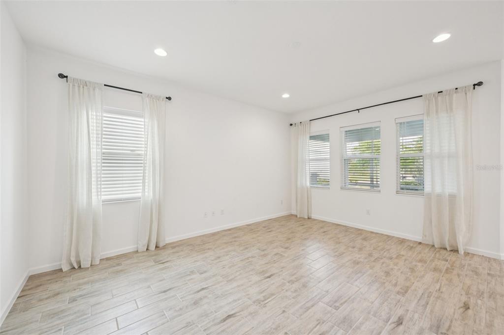 An empty room with white walls, wood-look tile flooring, and windows with white curtains — 806 WINTERSIDE DRIVE, APOLLO BEACH, FL