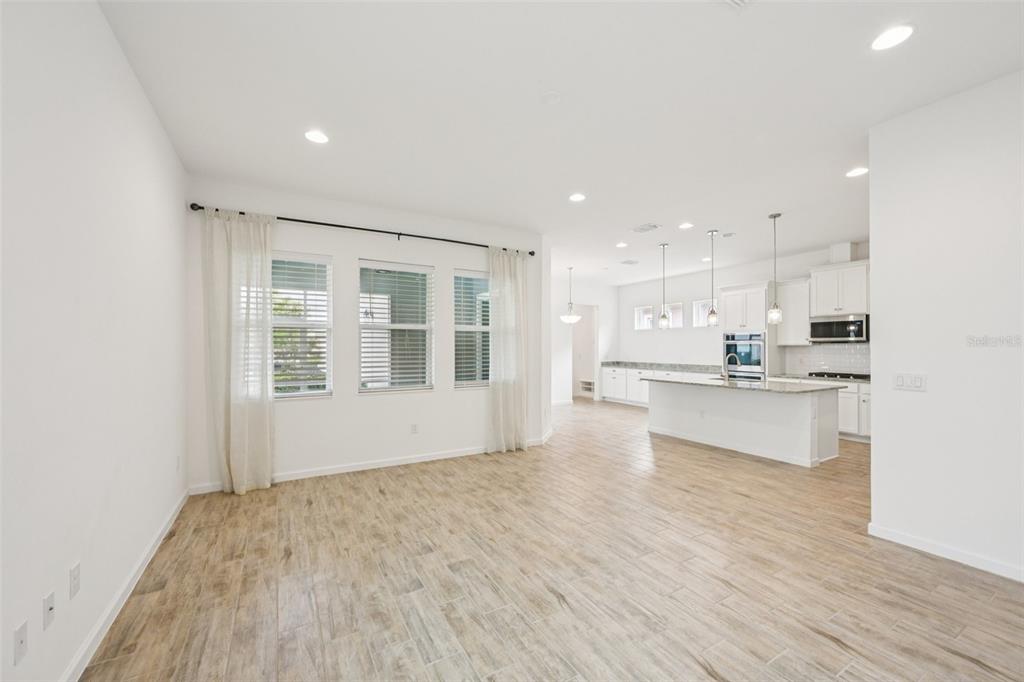 An open-concept living area features light wood-look tile flooring and a kitchen with an island — 806 WINTERSIDE DRIVE, APOLLO BEACH, FL